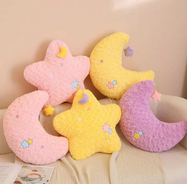 Moon and star shaped plushie pillows with no faces on a cutecore bed